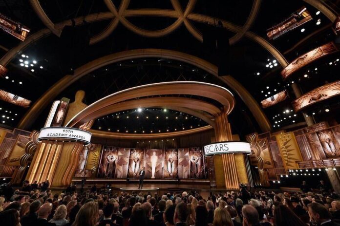 Decoração do palco da cerimônia do Oscar com elementos dourados, vermelhos e pretos.