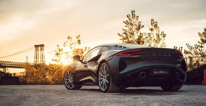 Um carro esportivo preto da Lotus Emira em um cenário urbano ao entardecer, destacando detalhes cromados