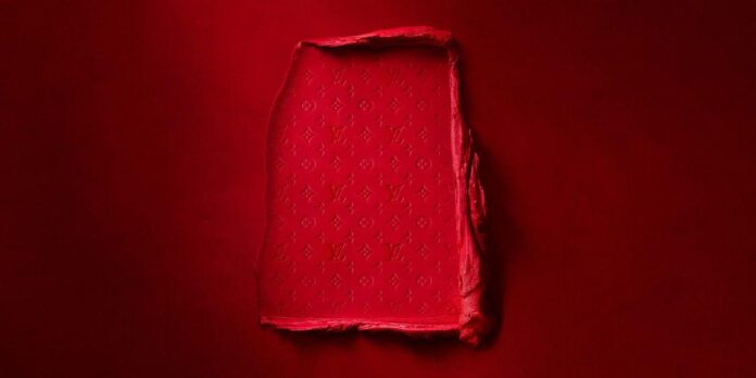 Uma imagem de um batom da Louis Vuitton com fundo vermelho liso.